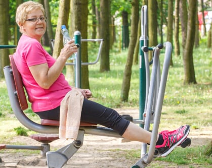older woman using park fitness equipment